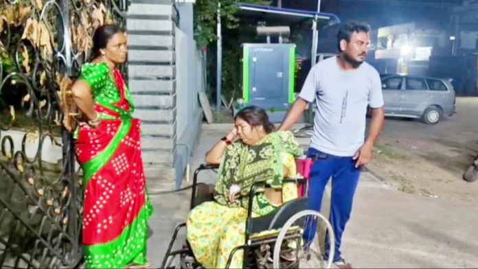 SON CARRIES MOTHER IN WHEELCHAIR